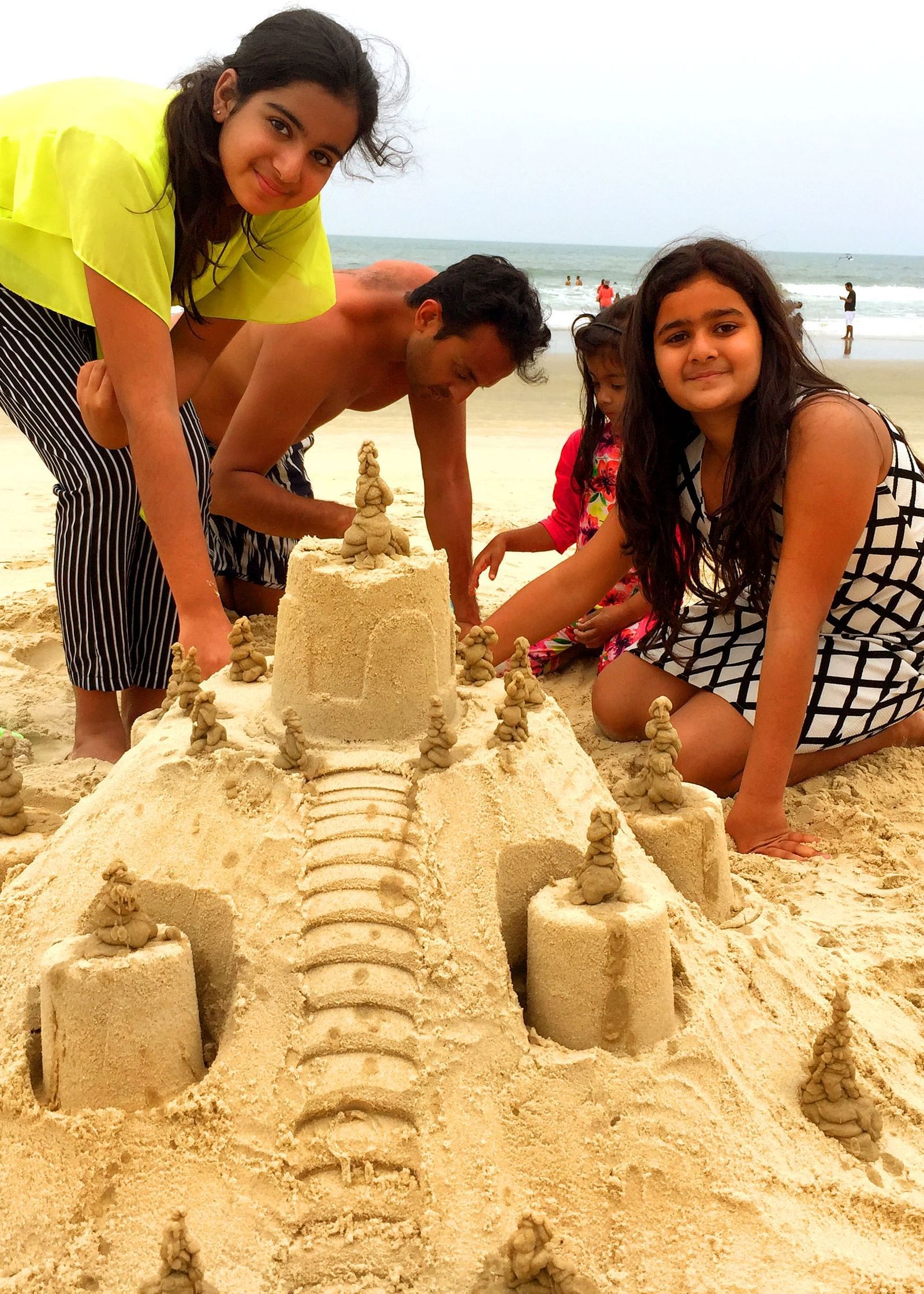 a group of people making a sandcastle on the beach - Caravela Beach Resort Goa