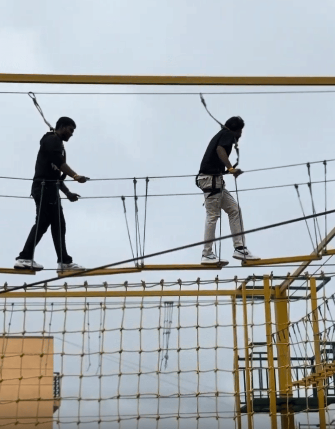 Guests crossing rope bridge during adventure activity at Nirantara Resort.