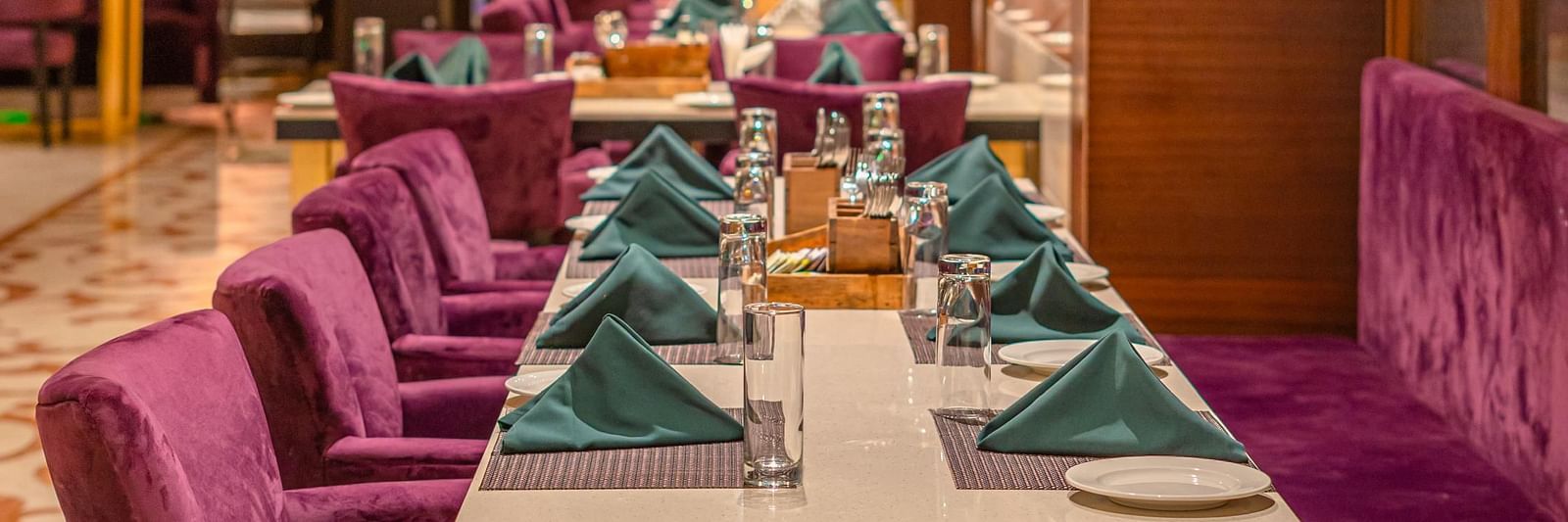 Cushioned chairs and a table set with exquisite culinary offerings for guests at Courtyard Fine Dine, Crescent Spa & Resort, Indore