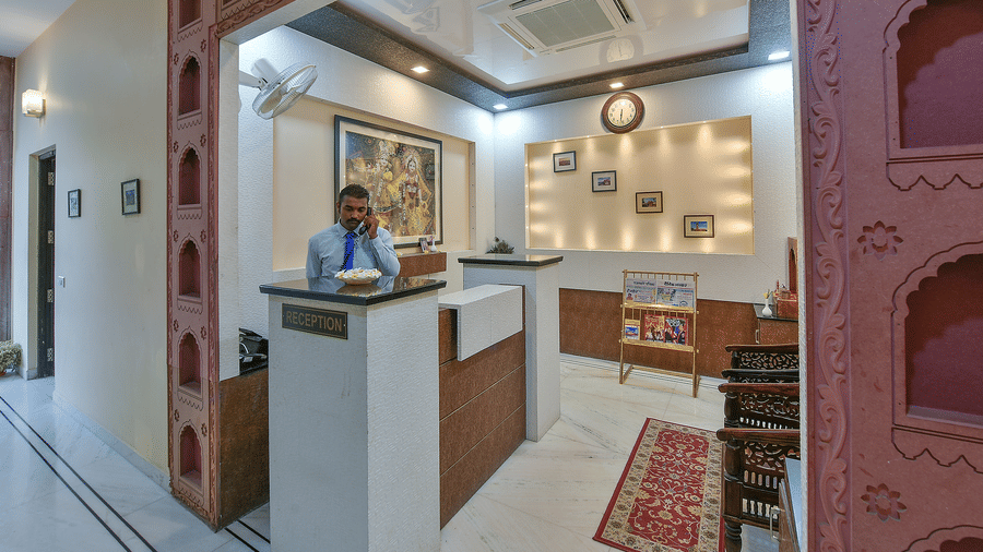 A receptionist stands behind a modern reception desk inside the lobby area at Garh Govind.