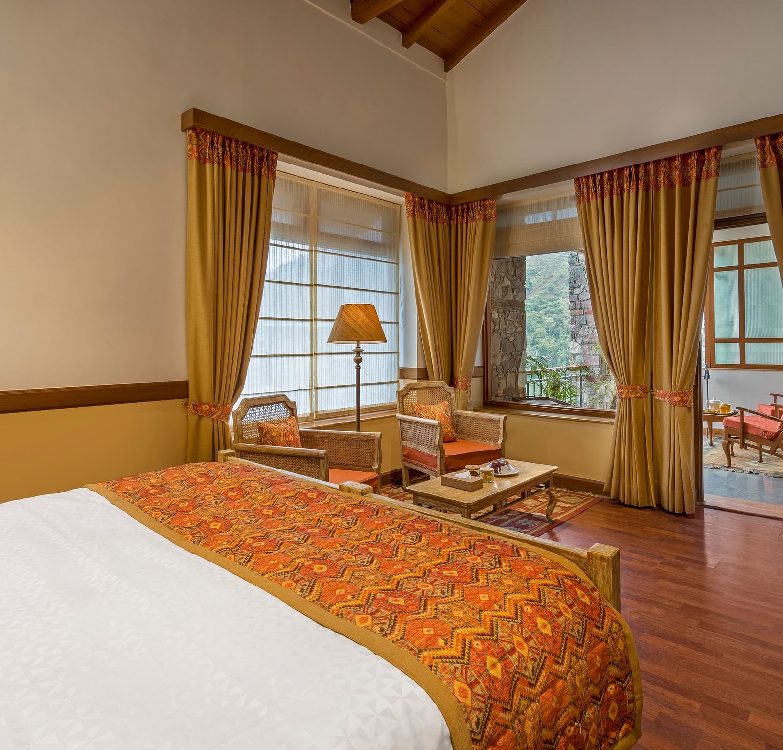 Top-side angle view of Superior Rooms at Fishermen's Lodge, Bhimtal, showcasing a plush bed, lamp stand, and flat-screen TV for a luxurious stay.