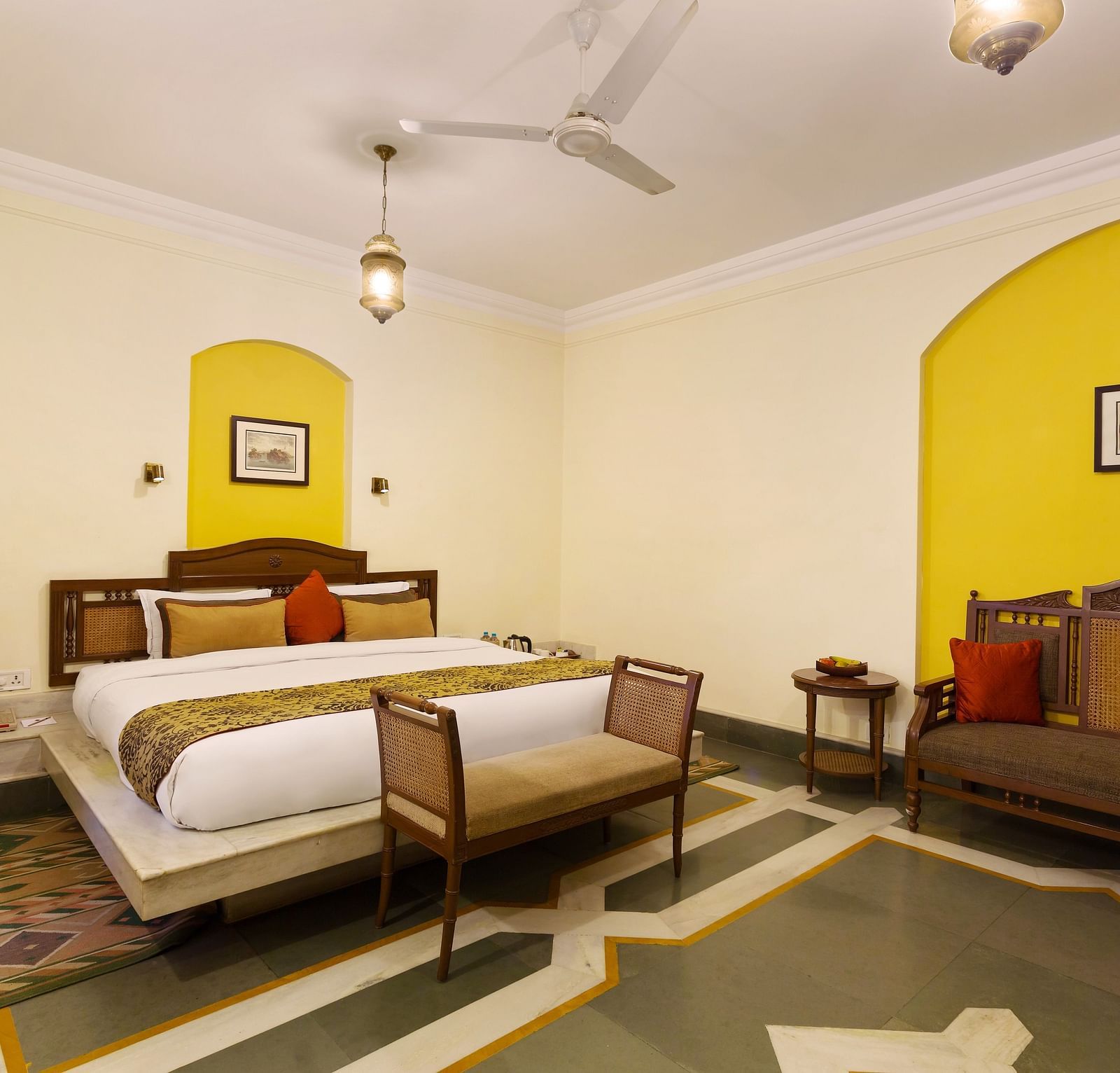 A room with white and yellow walls at The Haveli Hari Ganga in Haridwar is beautifully decorated with modern amenities, creating a bright and inviting atmosphere for guests to enjoy a comfortable stay.