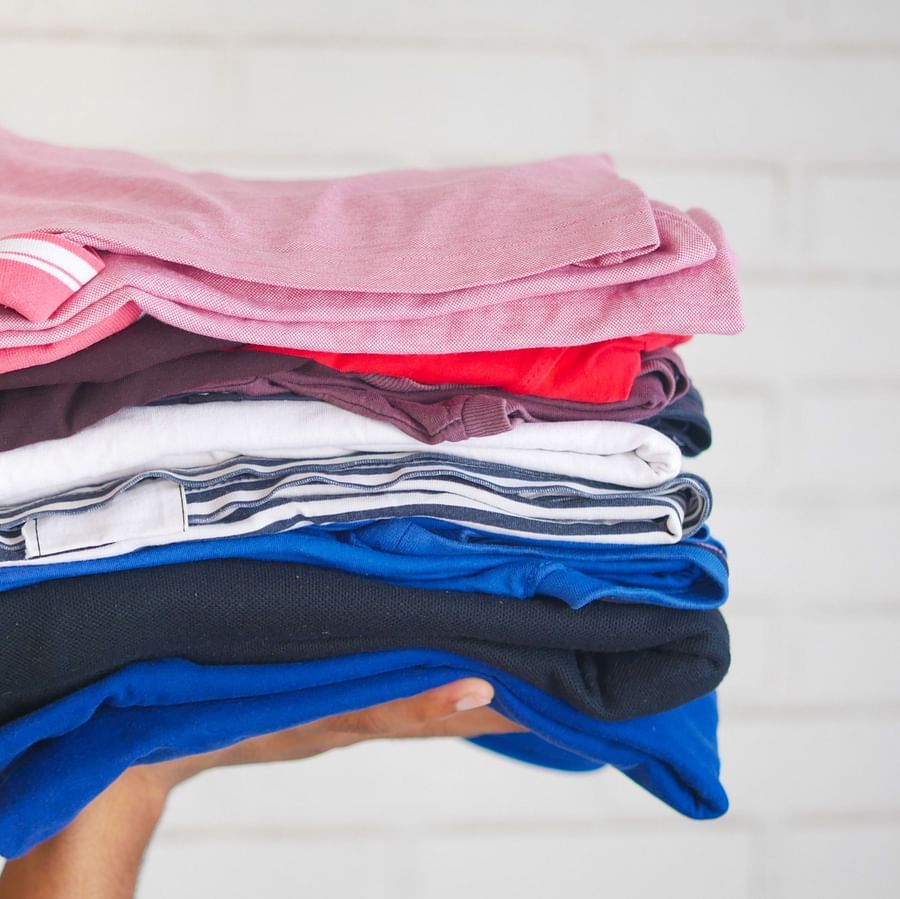 A hand holding a pile of neatly folded clothes