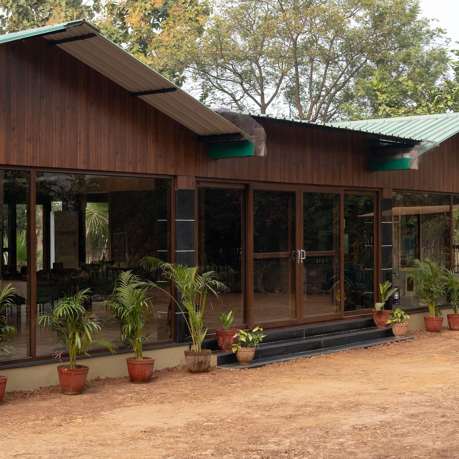 The charming main building of Aamaghati Jungle Retreat Ranthambore with a wide verandah and surrounding plants.