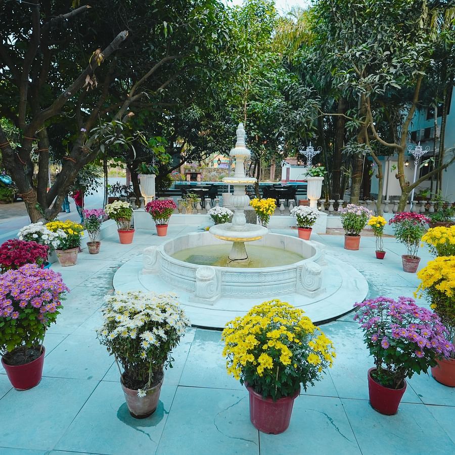 An image of a fountain surrounded by flower pots in a huge lawn at Rangamati Garden Resort