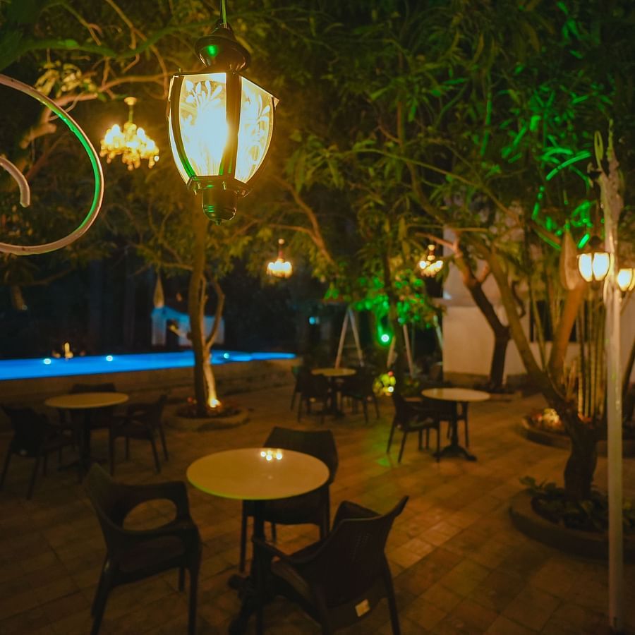 An image of outdoor garden featuring table and chairs set surrounded by trees at Rangamati Garden Resort
