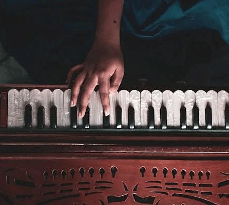 A top angle of a person playing the harmonium.