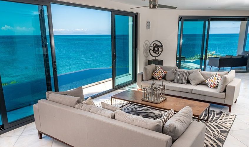 Modern ocean-view living room with floor-to-ceiling windows and luxury seating.