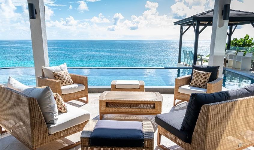 Outdoor seating area with ocean view and cushioned chairs at Tamarind Hills Resort and Villas - Antigua.