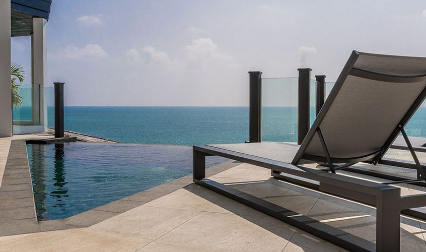 Luxury oceanfront deck with sun loungers beside a private infinity pool at Tamarind Hills Resort and Villas, overlooking the Sea.