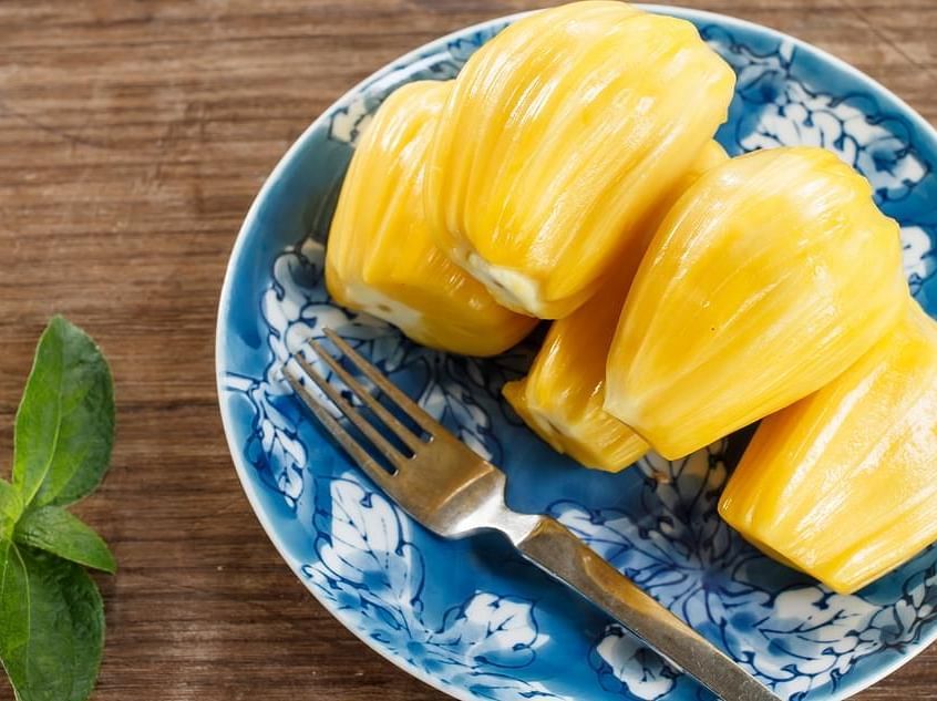 Plate of ripe jackfruit pieces on a blue ceramic dish with mint leaves.
