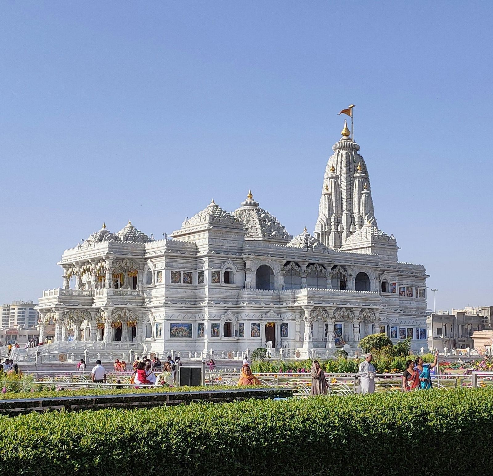 A facade of Prem Mandir in Vrindavan during the day time as devotees are strolling around premises embellished with flora and fauna