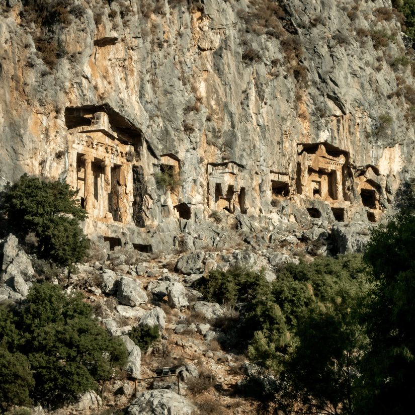 A view from afar of entrance to different caves on the side of a cliff with boulders fallen in front of it. The Pandavleni Caves' History dates back to 3rd century BCE.