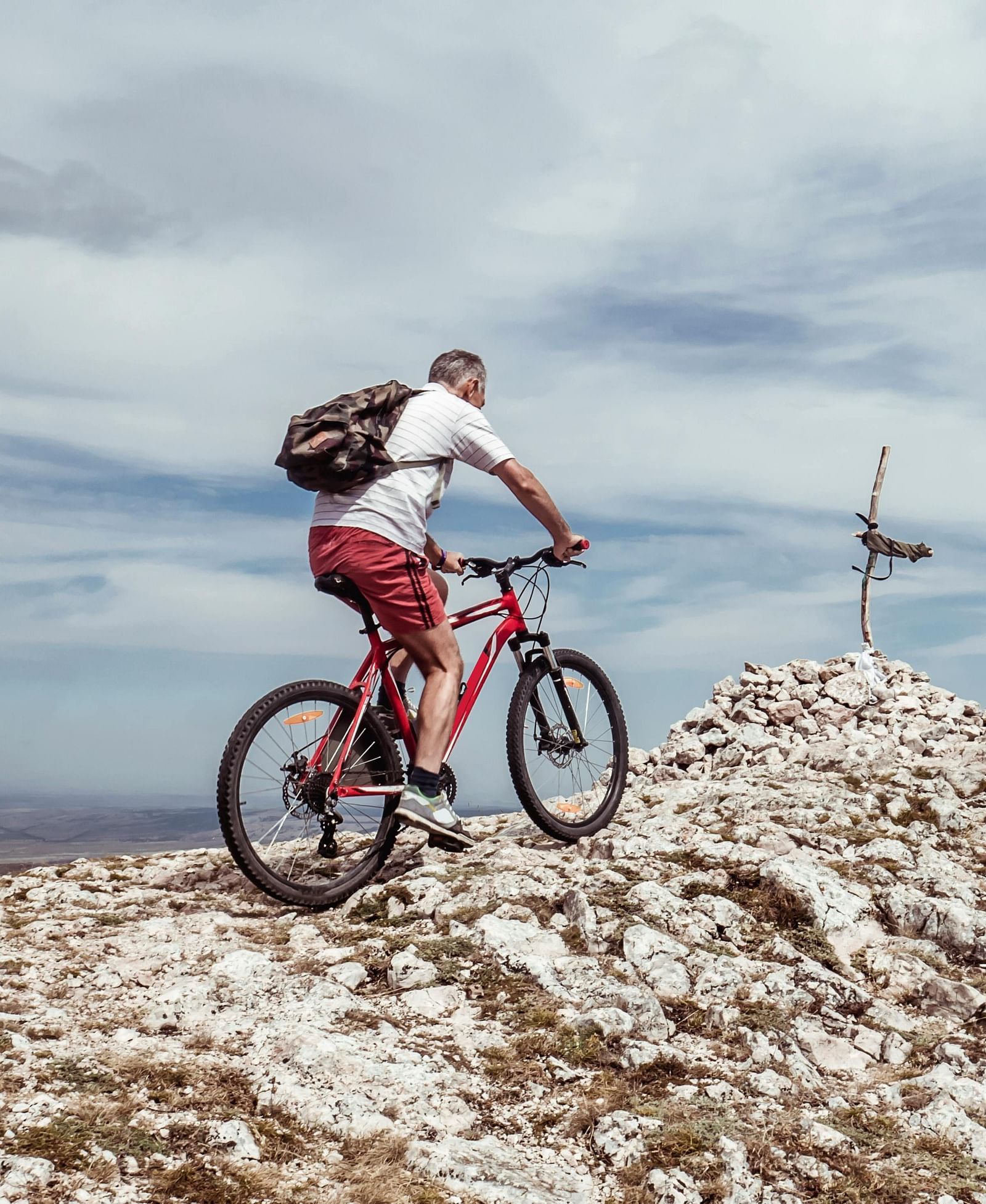 Cyclist riding on rocky terrain under a dramatic sky.