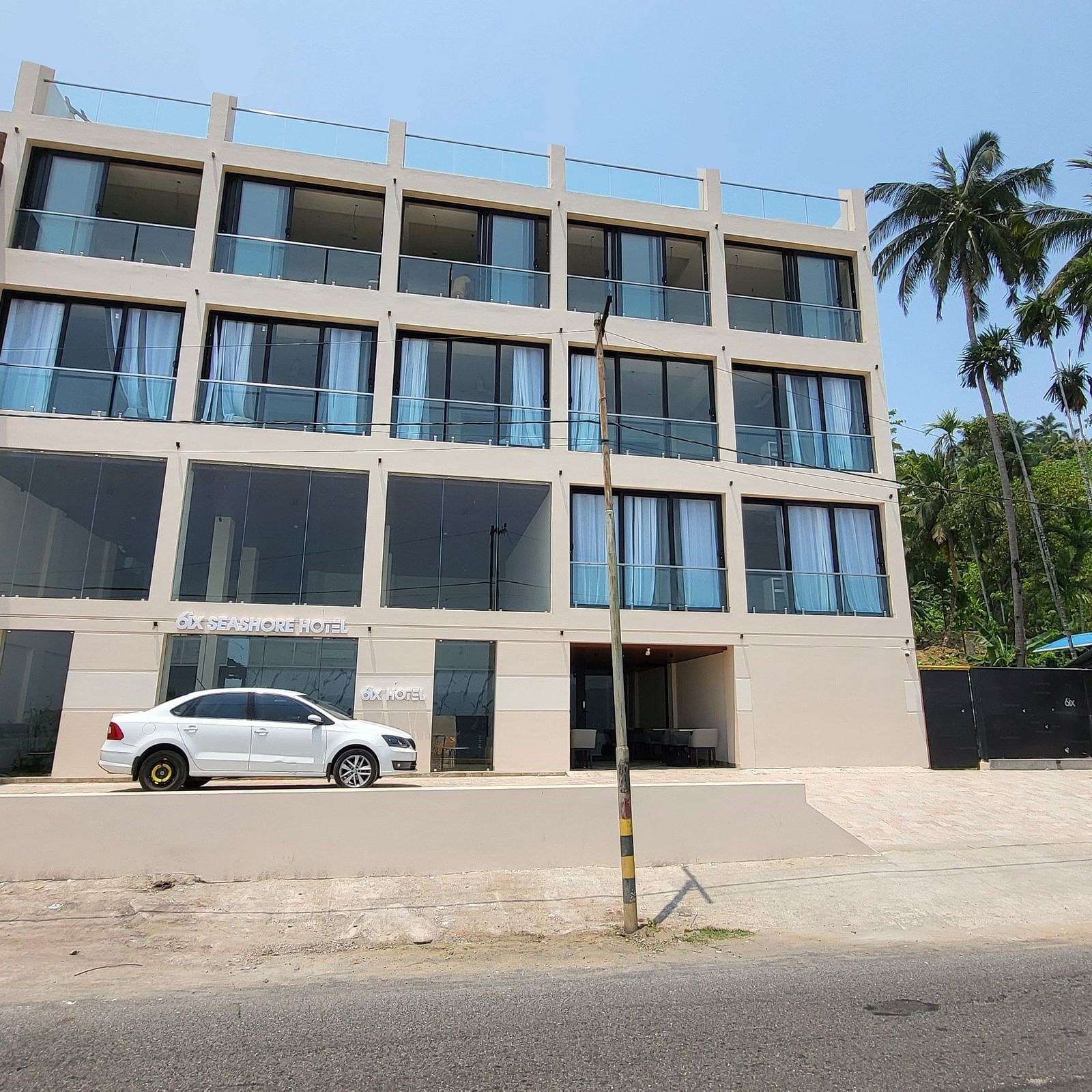 Facade of 6ix Seashore Hotel, Port Blair with a car standing in front of it