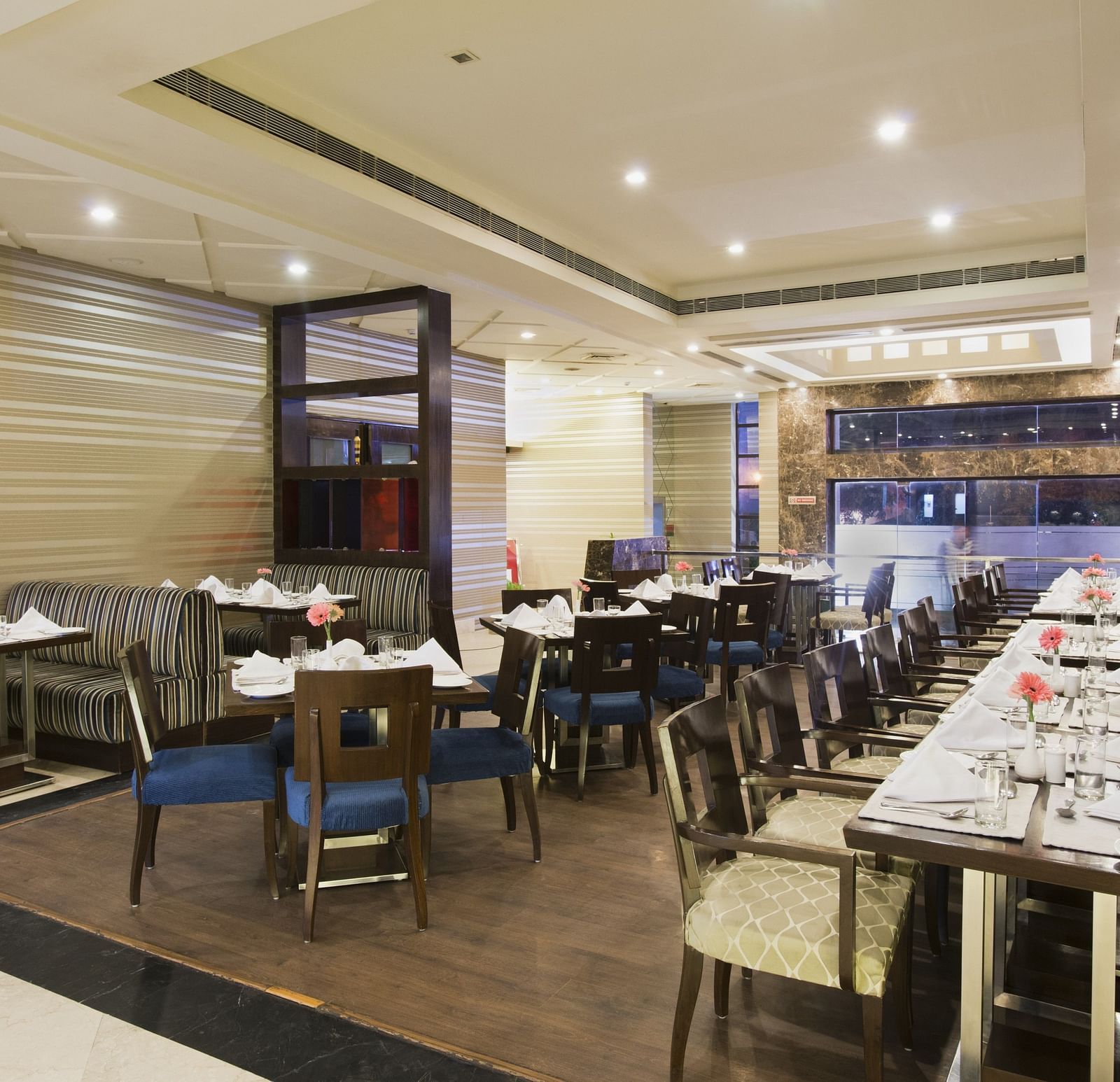 A closed dining space at The Manor Bareilly featuring multiple wooden tables and chairs arranged for a dining experience
