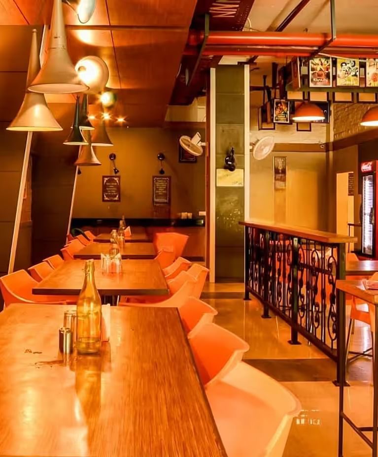 View of Mumbai Masala Restaurant with a warm ambience, wooden table and chairs, and stylish lighting- Max Hotel Prayagraj.