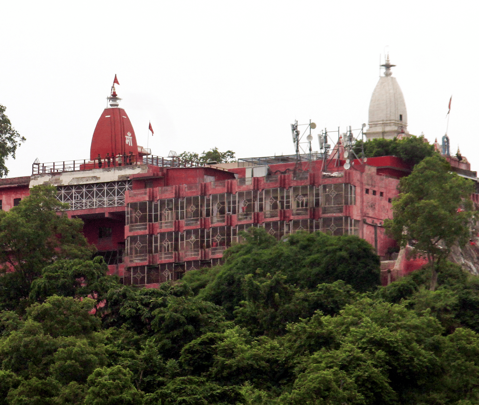 Hilltop temple complex surrounded by dense trees under a clear sky