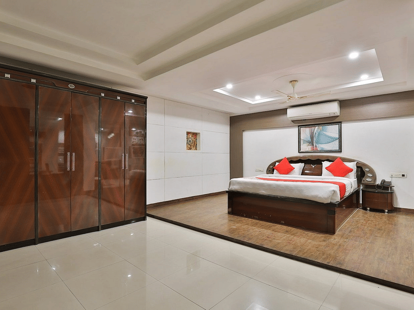 An overview of the Premium Suite with a king bed, a wall mounted AC, side tables and a large wardrobe in view at VITS Select, Bharuch.
