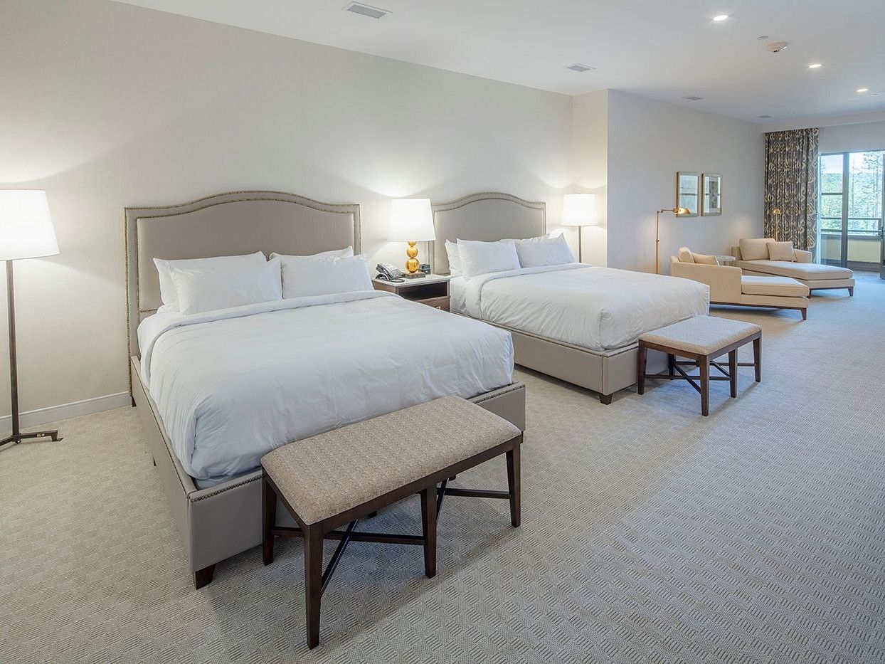 interiors of suite at Yo1 featuring two plush beds and divans with warm lighting and a seating space in the background