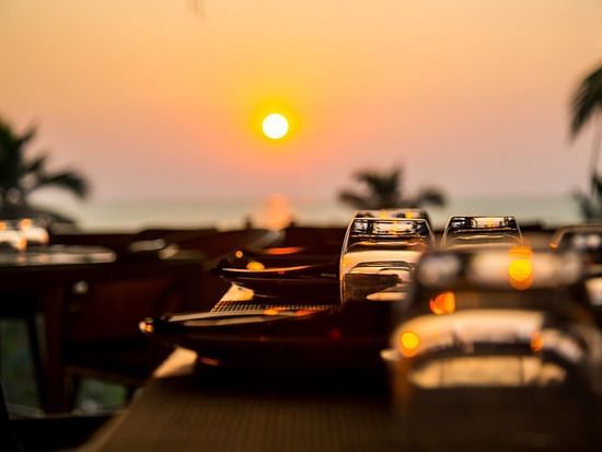 sunset view can be enjoyed from a restaurant open dining area with empty tables - Stone Wood Hotels & Resorts