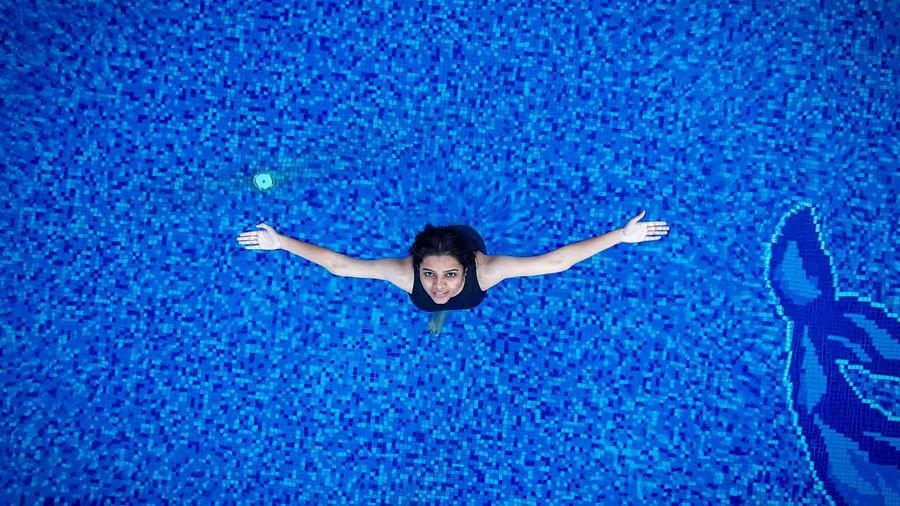 Top view of a girl with her hands spread out at the outdoor swimming pool in Coorg Jungle Camp Backwater Resort in Kushalnagar.