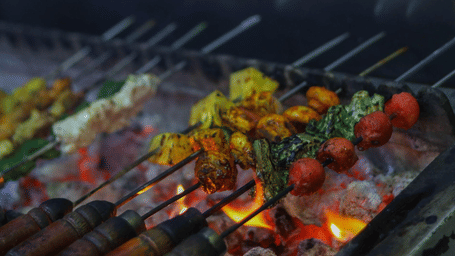 Close-up of skewers with marinated vegetables and meat being prepared on a live charcoal grill - Jenneys Residency, Coimbatore