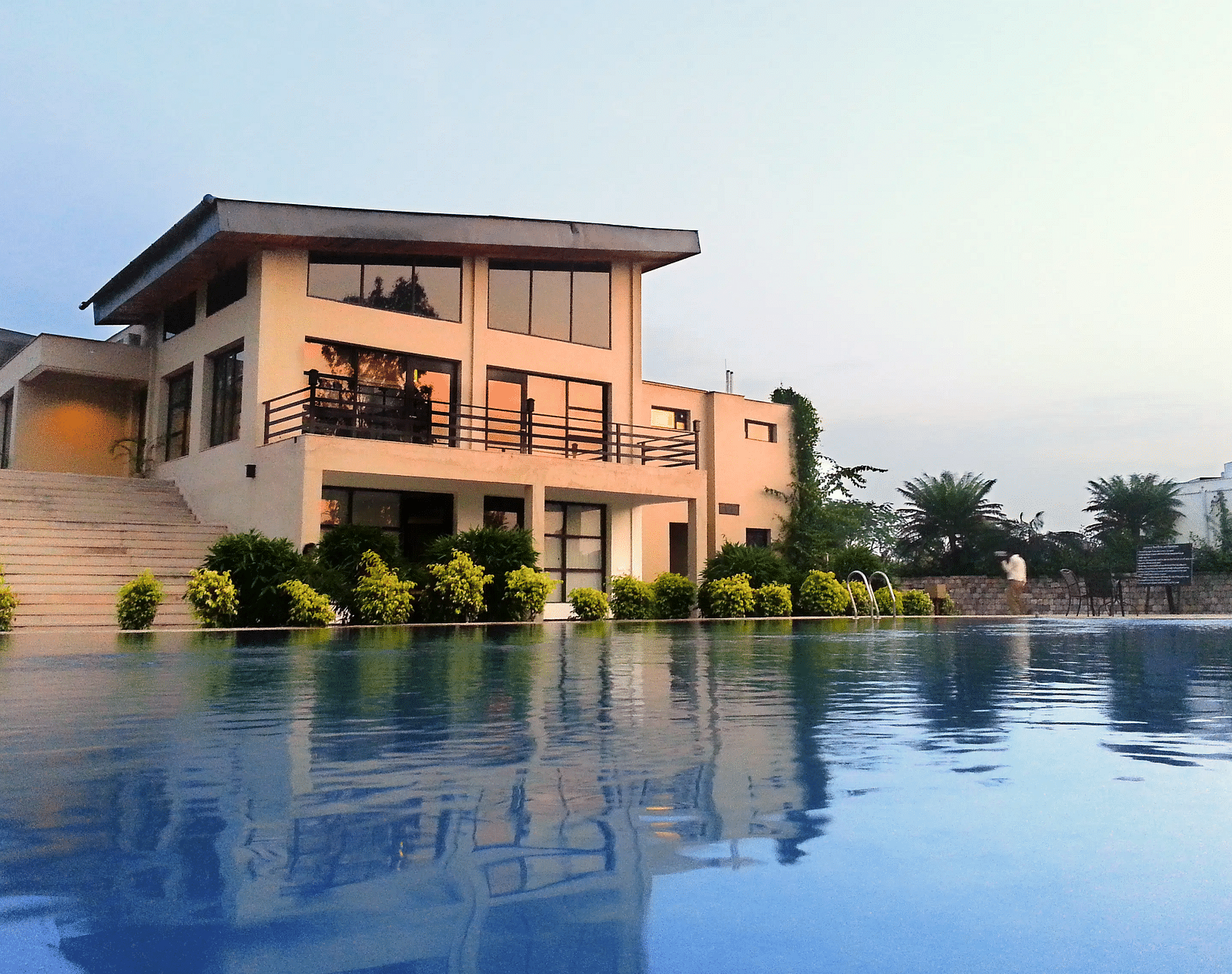 Facade shot of the Golden Tusk featuring a calm swimming pool in the foreground during early evening hours - Ivory Destinations