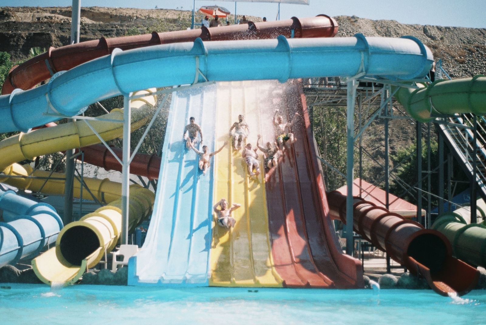 A multi-lane water slide with people riding down it in Water Kingdom.