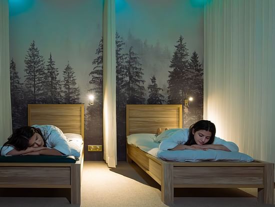 Tranquil quiet room with twin massage beds, forest mural backdrop, and ambient lighting at The Manor Wellness & Sports Hotel