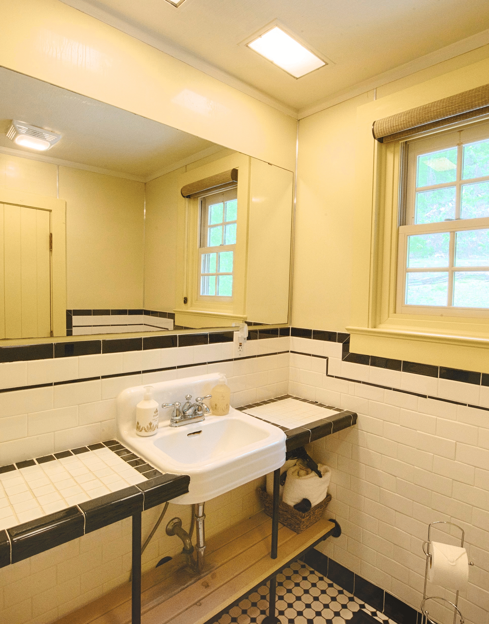 a wash basin with a wide mirror above it and a small closed window beside it in a bathroom - Historic Tapoco Lodge