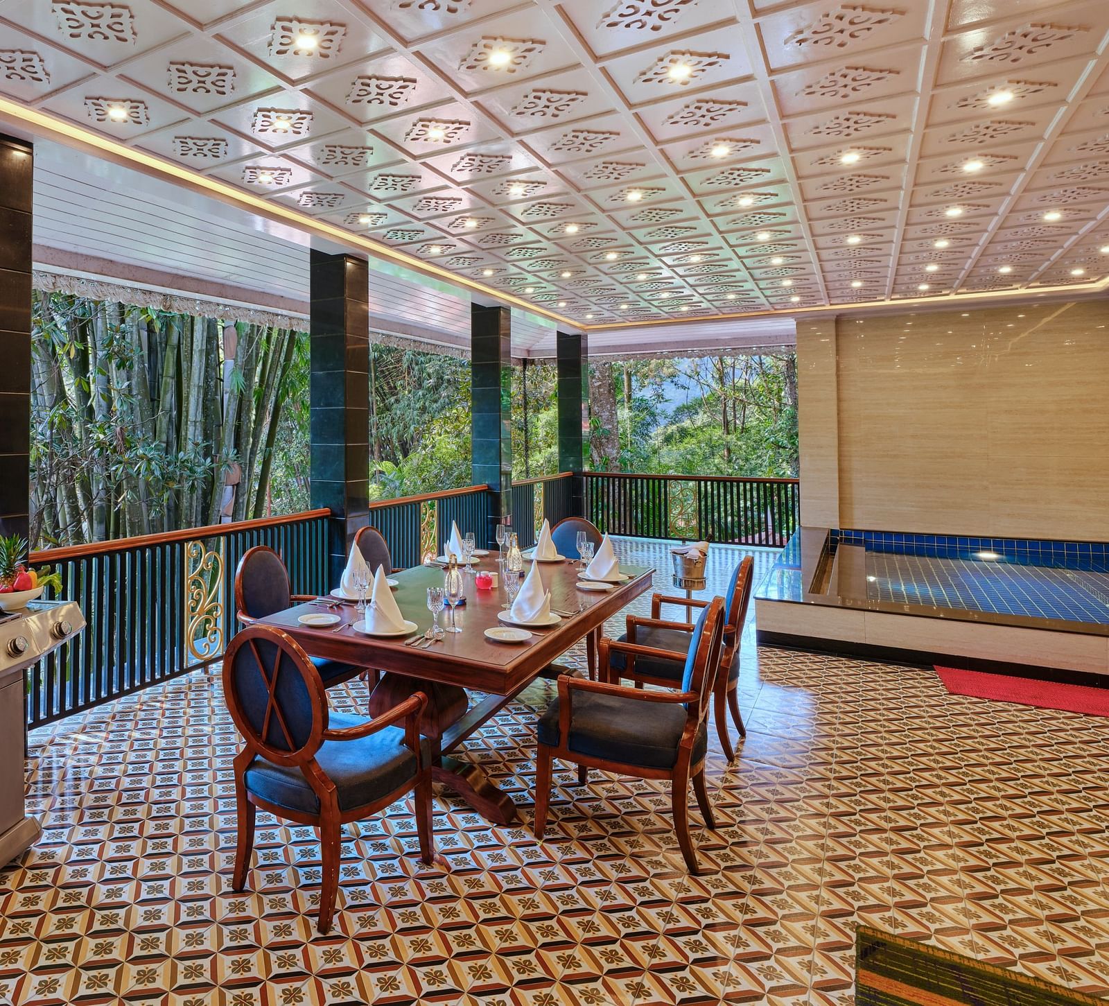 Regent villa outdoor dining area with a barbecue grill, table, chairs and a swimming pool.