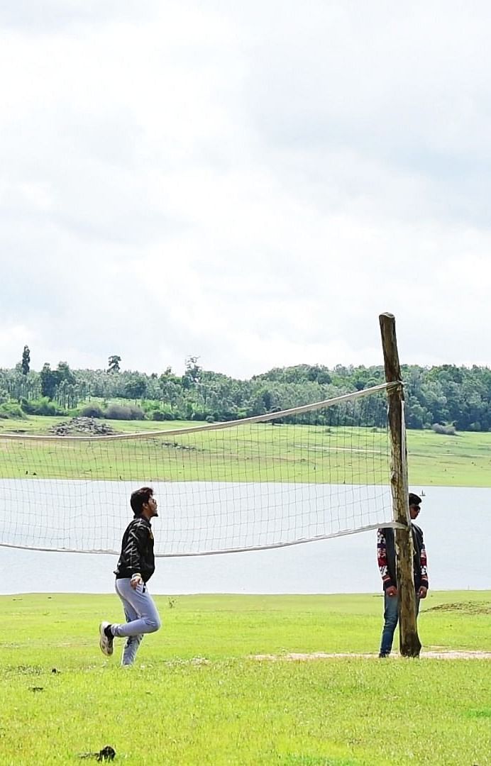 Image of a group of people playing volleyball beside a water body at Coorg Jungle Camp Backwater Resort, Kushalnagar.