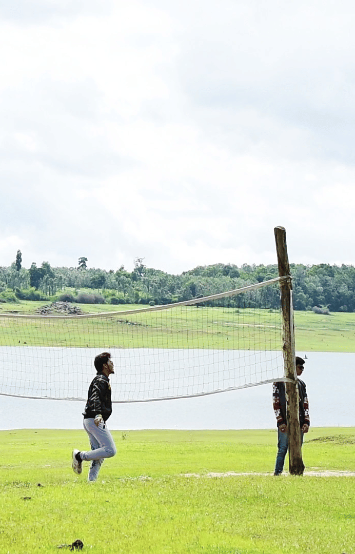 Image of a group of people playing volleyball beside a water body at Coorg Jungle Camp Backwater Resort, Kushalnagar.