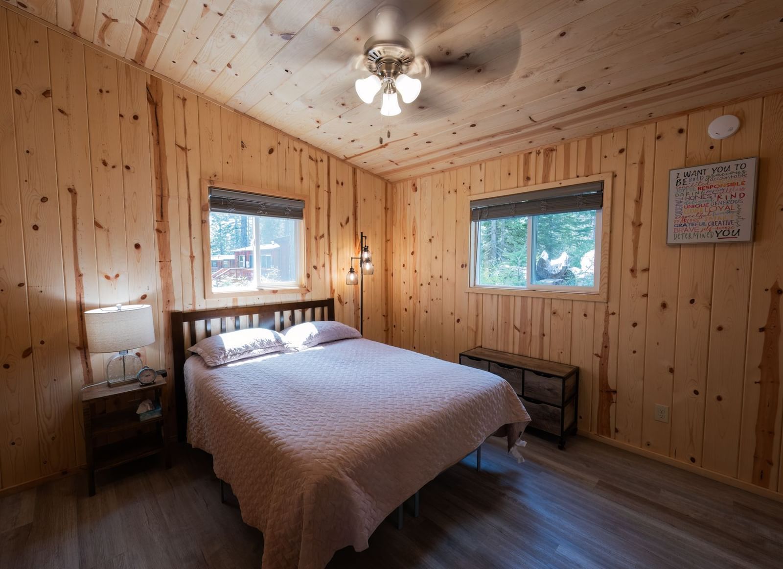 Bedroom with a queen bed, wooden walls, and ceiling fan offering a warm rustic stay at Kit Carson Lodge.