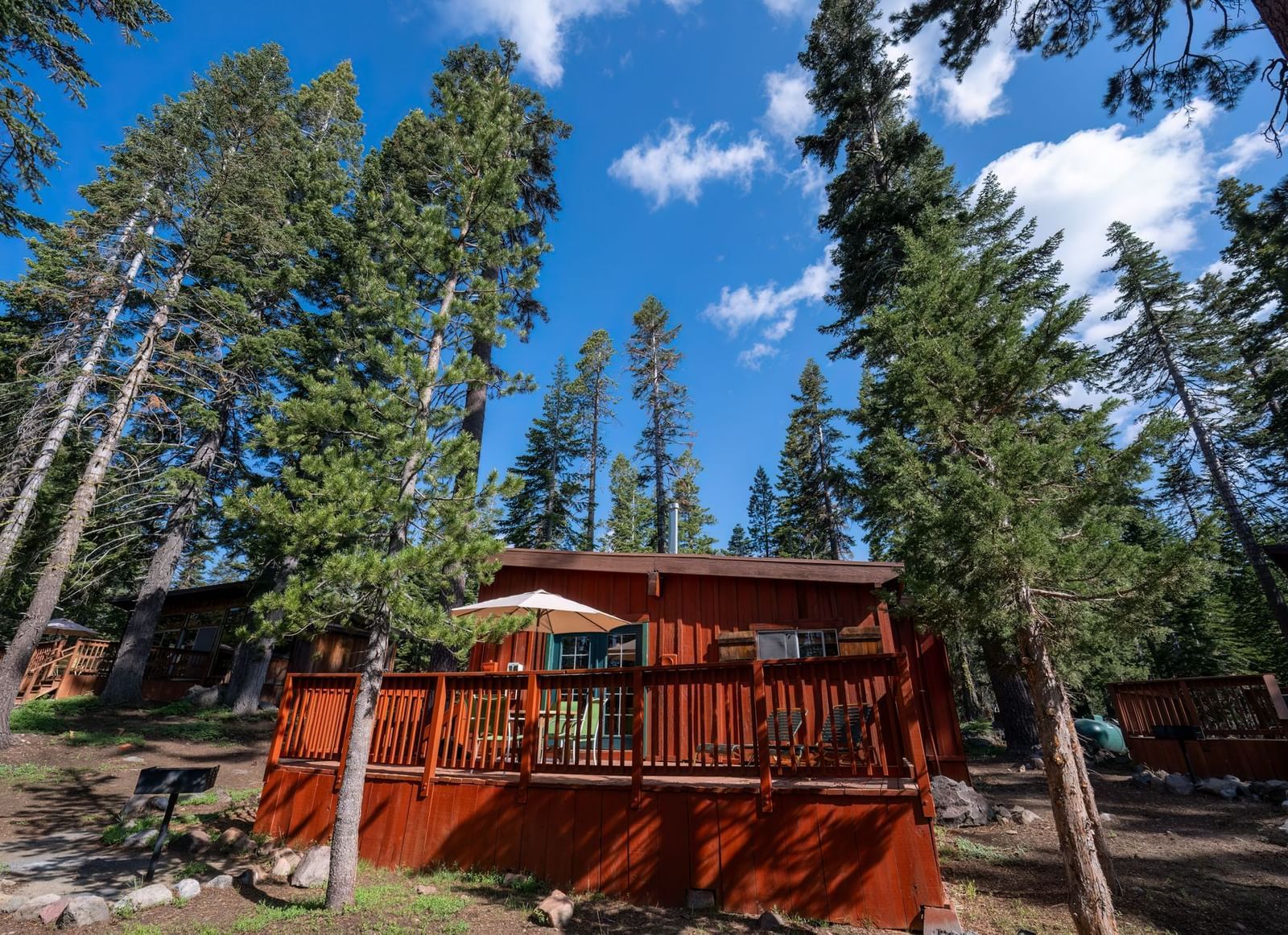 Scenic forest cabin exterior with red wood siding surrounded by trees at Kit Carson Lodge.
