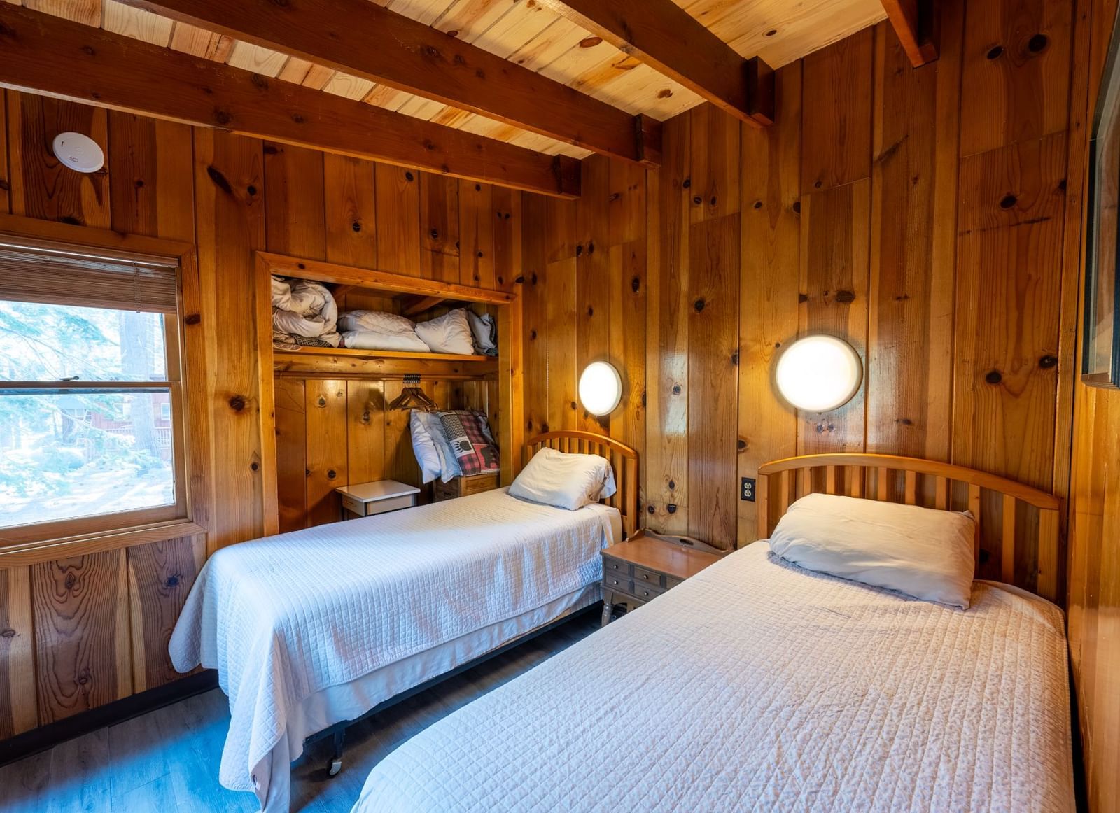 Narrow wood-walled bedroom with twin beds and reading lights at Kit Carson Lodge.