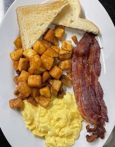 a complete breakfast of bacon with scrambled eggs served with diced potatoes and toasted bread - Historic Tapoco Lodge