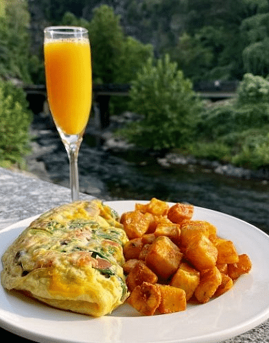 a fluffy omelette served with a glass of fresh orange juice besides the river - Historic Tapoco Lodge