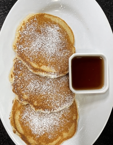 a white porcelain plate with three pancakes served with a small bowl of maple syrup - Historic Tapoco Lodge