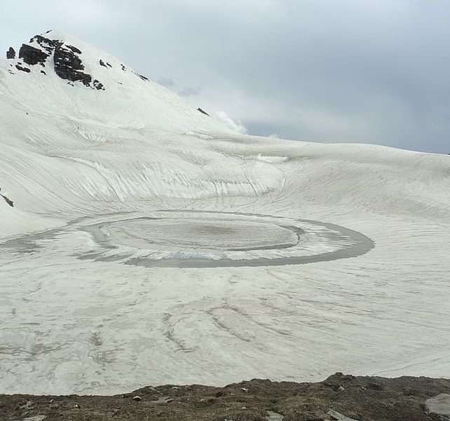 Bhrigu Lake covered in snow and a misty sky