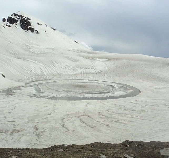 Bhrigu Lake covered in snow and a misty sky
