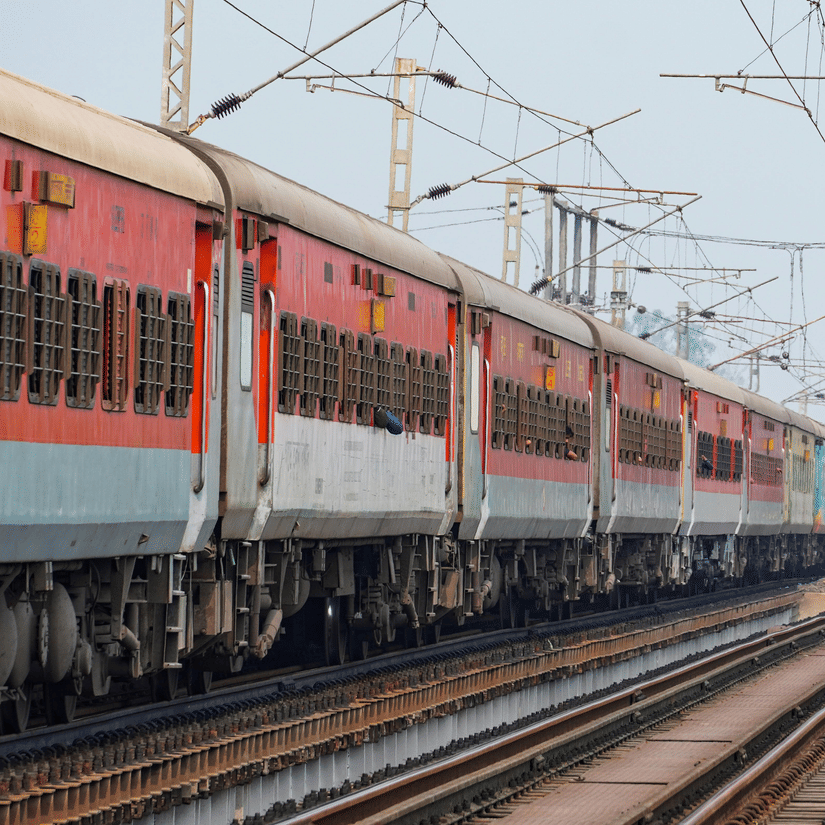 A passenger train travelling along railway tracks beneath electric lines