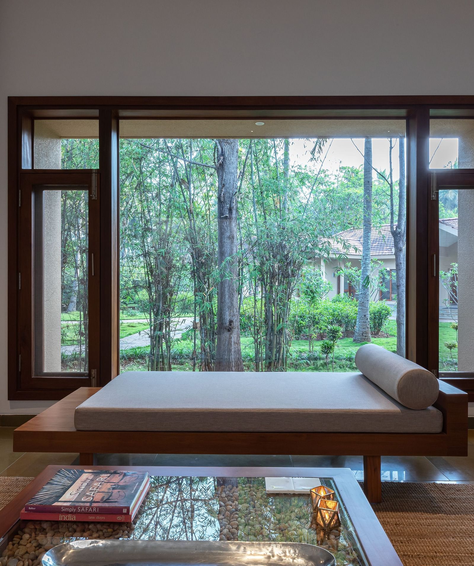 Bedroom with a low bed, glass table, and large window, natural light, modern design - Shreyas Retreat