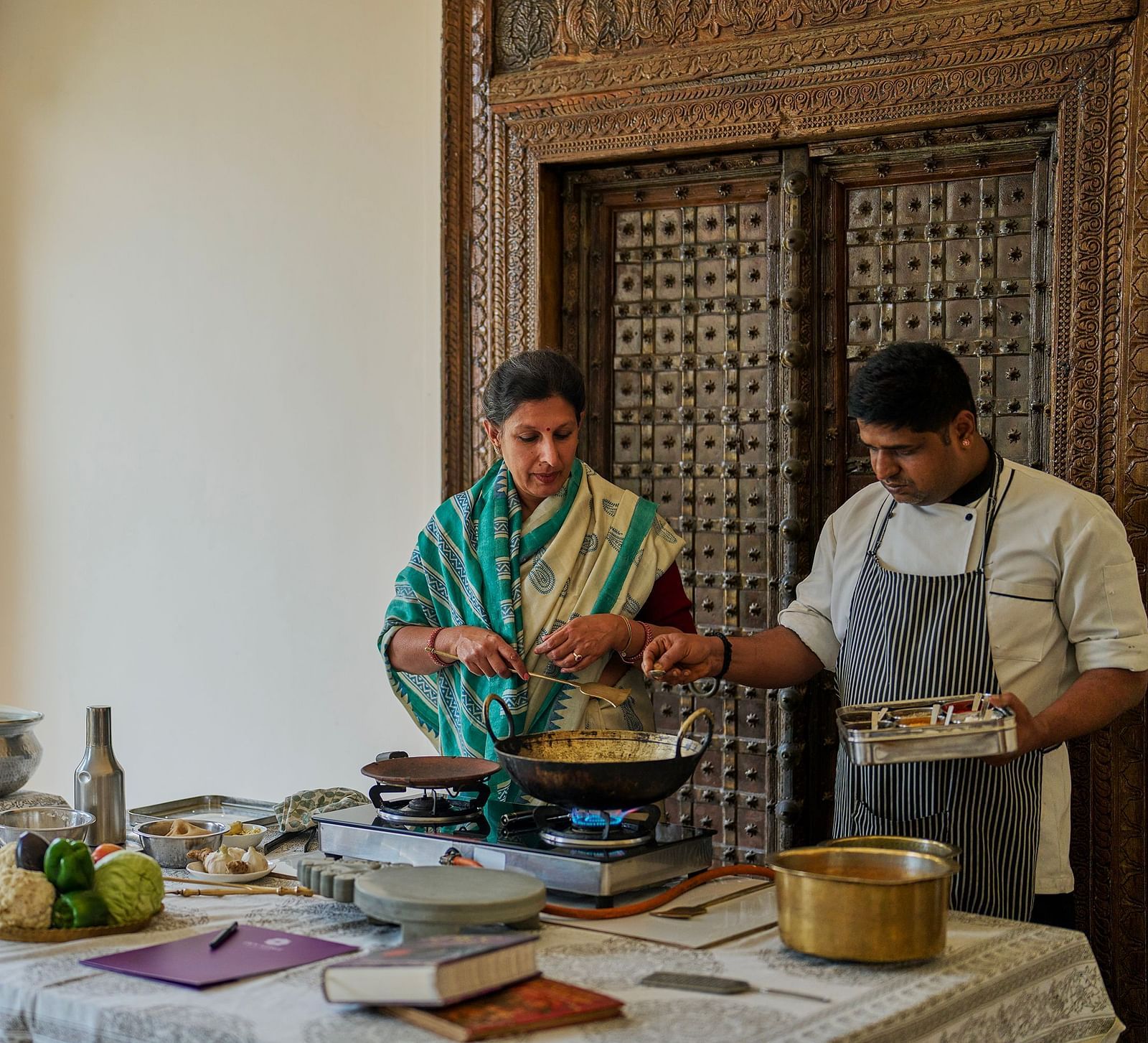 an image of a woman taking culinary classes at Dev Shree, Deogarh along with a trained chef
