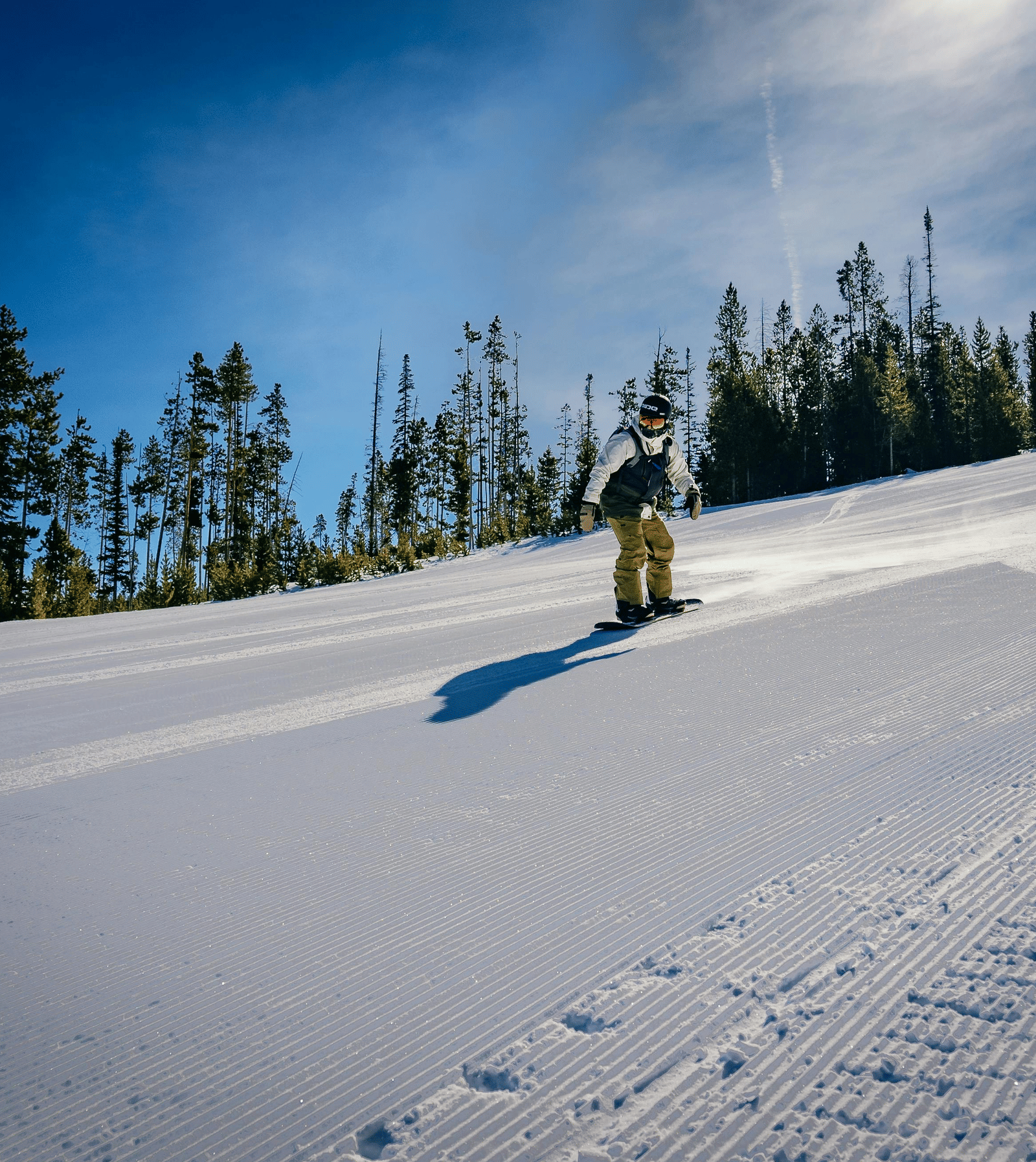 A person skiing on a snow covered mountain with pine trees surrounding it.