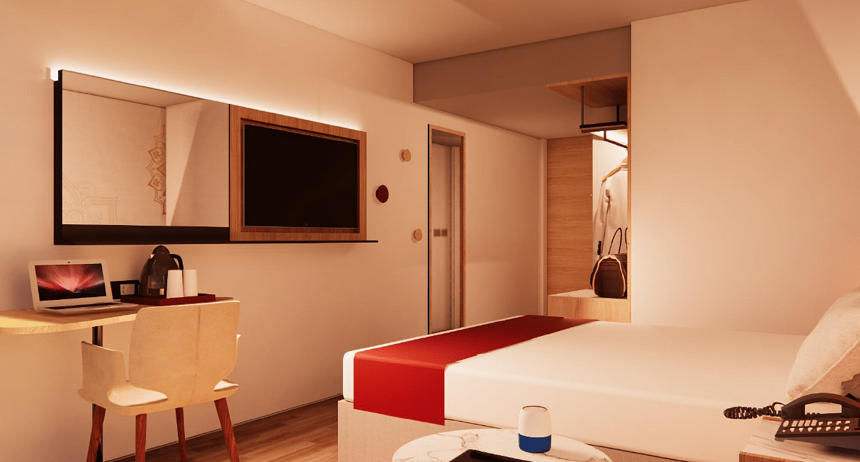 A close up shot of a room at TGI Oberon, Koramangala, highlighting a bed, flat screen TV, a work desk, a chair, and a tea coffee maker