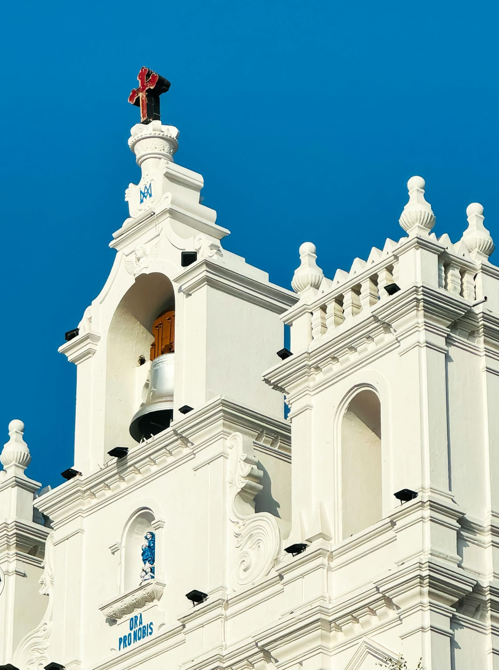 A close-up shot of a white-coloured church building with a plain blue sky in the background.