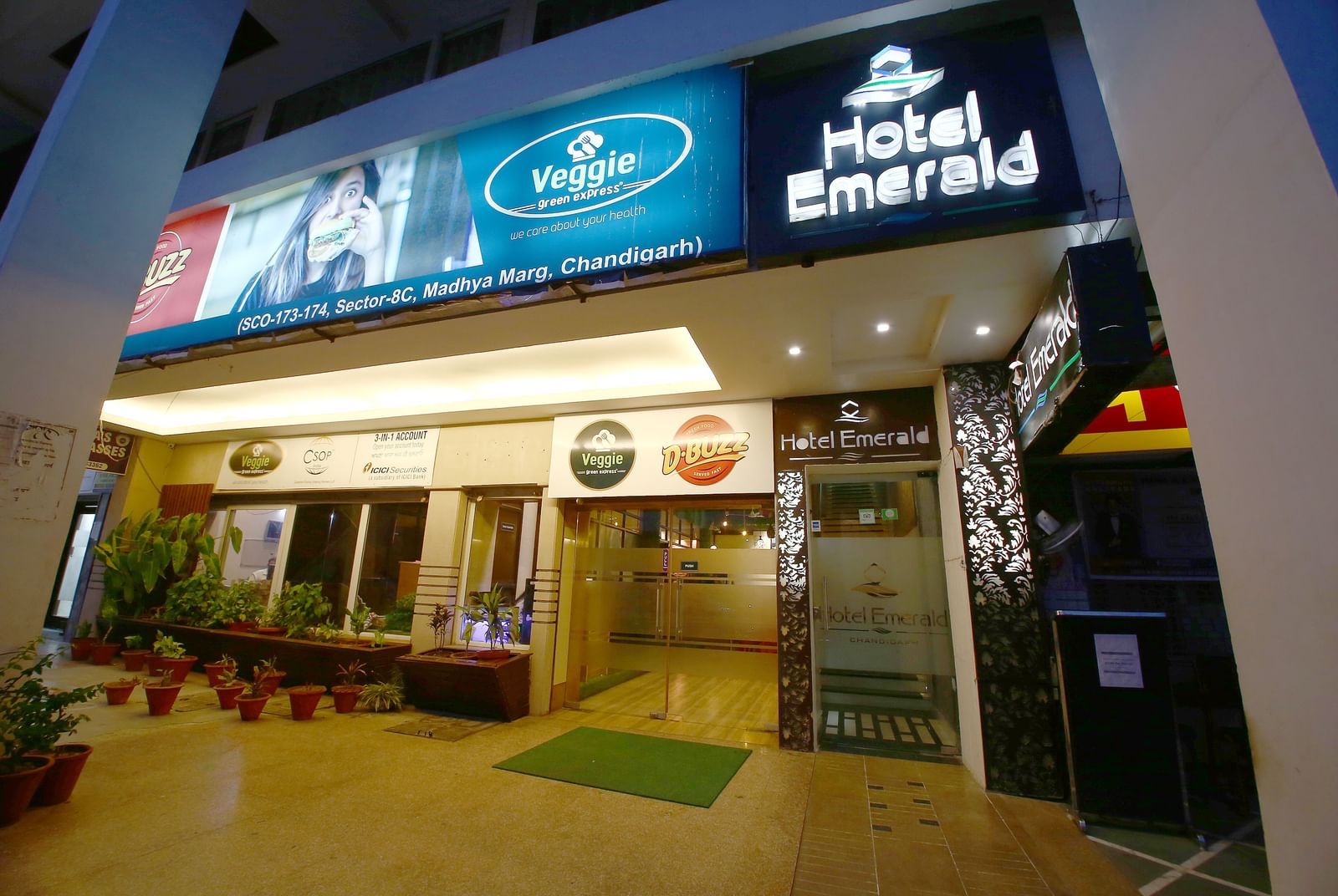 Illuminated entrance of Hotel Emerald at night with hotel signage
