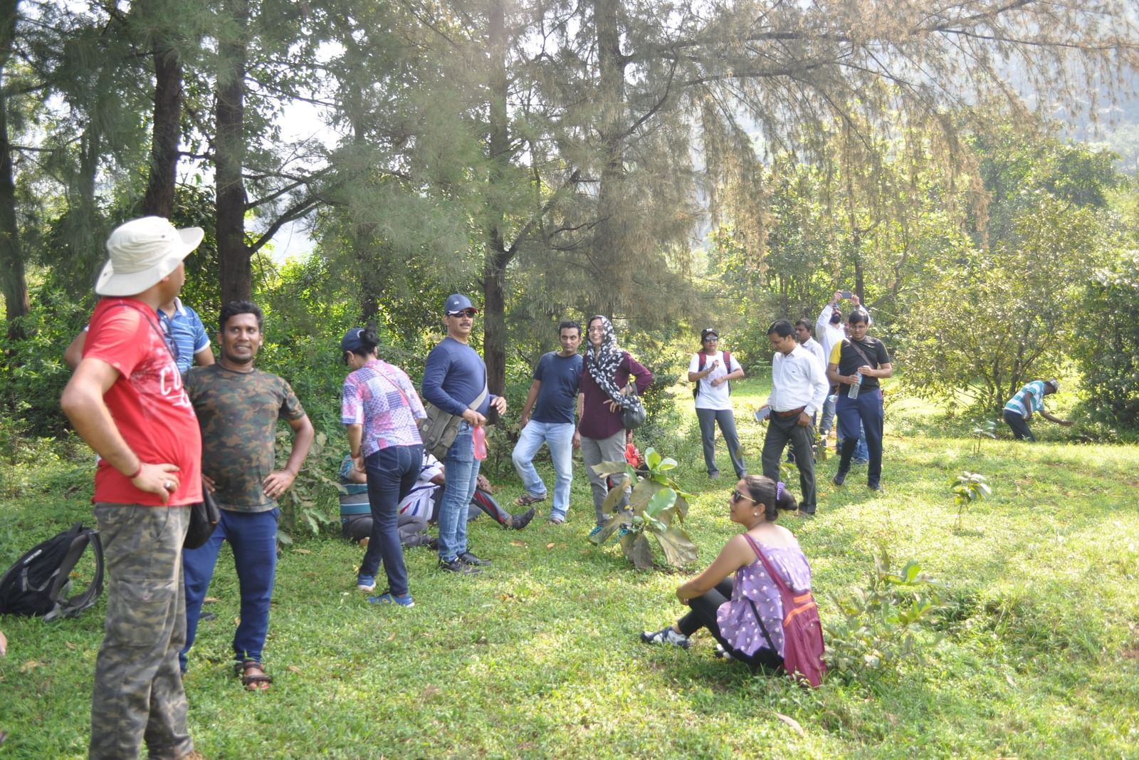 A group of people are engaged in an outdoor activity at Forest Escapes Koyna, with some individuals carrying others on their shoulders.